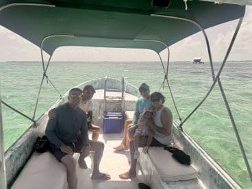A joyful family enjoys a day on the water aboard a small boat, surrounded by beautiful turquoise waters — perfect for creating lasting memories together.