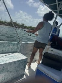 A woman enjoys fishing from a boat, showcasing the excitement of on-water activities in a scenic environment.