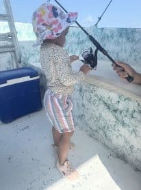 A young child enjoys fishing on a boat, showcasing a delightful family experience on the water.