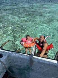 A joyful moment as a mother and her child enjoy swimming in crystal-clear waters, showcasing a fun family experience in a tropical paradise.