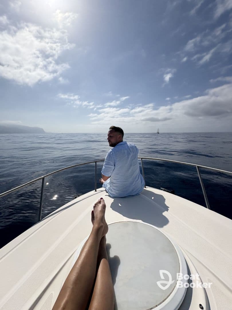 A couple enjoys a serene moment on the bow of a yacht, soaking in the sun and ocean views — perfect for a romantic getaway or relaxing day on the water.