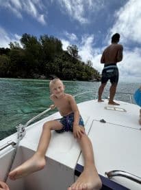 A cheerful child enjoys a sunny day on a boat, with a beautiful island backdrop — perfect for family adventures on the water.