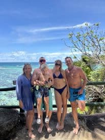 A joyful family poses together against a stunning ocean backdrop, capturing a memorable vacation moment by the beach.