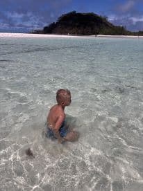 A young boy enjoys playing in the crystal-clear waters of a beautiful beach, creating unforgettable memories in a tropical paradise.