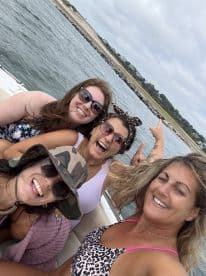A joyful group of friends poses for a fun selfie on a boat, capturing the essence of a memorable day on the water.