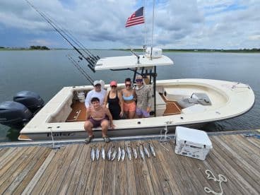 A group of friends celebrates a successful fishing trip on a Parker boat, showcasing their catch on the dock — perfect for memorable fishing adventures.
