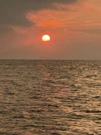 A stunning sunset casts vibrant colors over the tranquil sea, creating a picturesque backdrop perfect for evening boat cruises.
