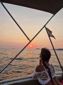 A woman enjoys a serene sunset view from the deck of a boat, creating a perfect backdrop for romantic moments on the water.