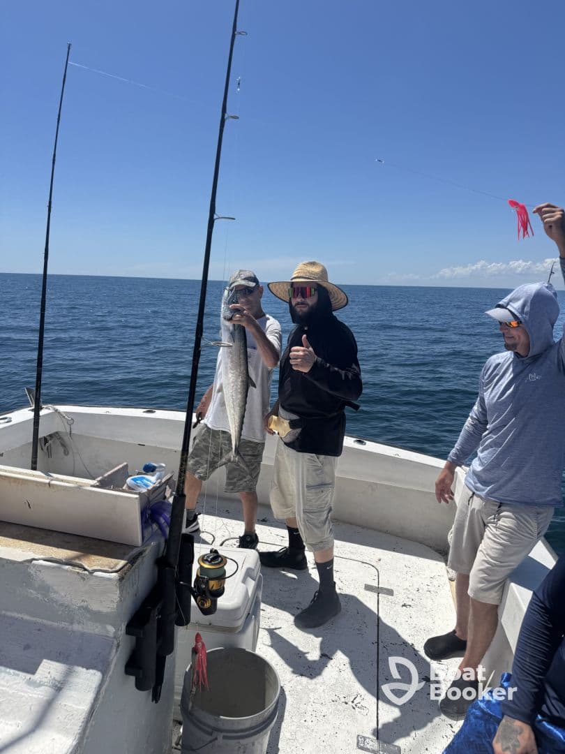 A group of friends celebrates a successful fishing trip, showcasing their catch aboard a boat in the open ocean — a perfect day for fishing enthusiasts.