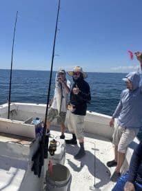 A group of friends celebrates a successful fishing trip, showcasing their catch aboard a boat in the open ocean — a perfect day for fishing enthusiasts.