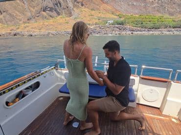 A romantic proposal takes place on a boat, capturing a special moment between a couple against a stunning natural backdrop.