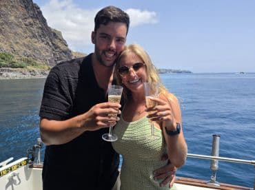 A happy couple celebrates with cocktails on a yacht, surrounded by stunning ocean views — perfect for romantic getaways or special occasions.