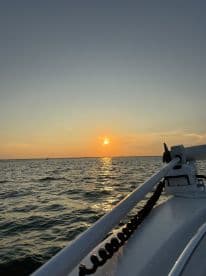 A serene sunset view from the deck of a boat, showcasing the tranquil waters and the fading daylight — perfect for evening cruises.