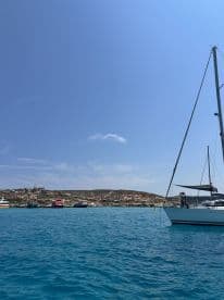 A scenic view of a sailboat anchored near a picturesque island, with people enjoying the beautiful turquoise waters — perfect for a relaxing day on the water.
