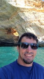 A man takes a selfie with a stunning ocean cave in the background, showcasing the beauty of the coastal scenery — perfect for adventure seekers exploring the waters.