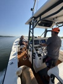 A group of friends enjoys a day on the water aboard a boat, with one person at the helm and a dog lounging nearby — perfect for a fun-filled boating adventure.