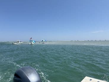 A vibrant scene at a sandbar with boats anchored nearby, showcasing a perfect day for water activities and relaxation under the sun.