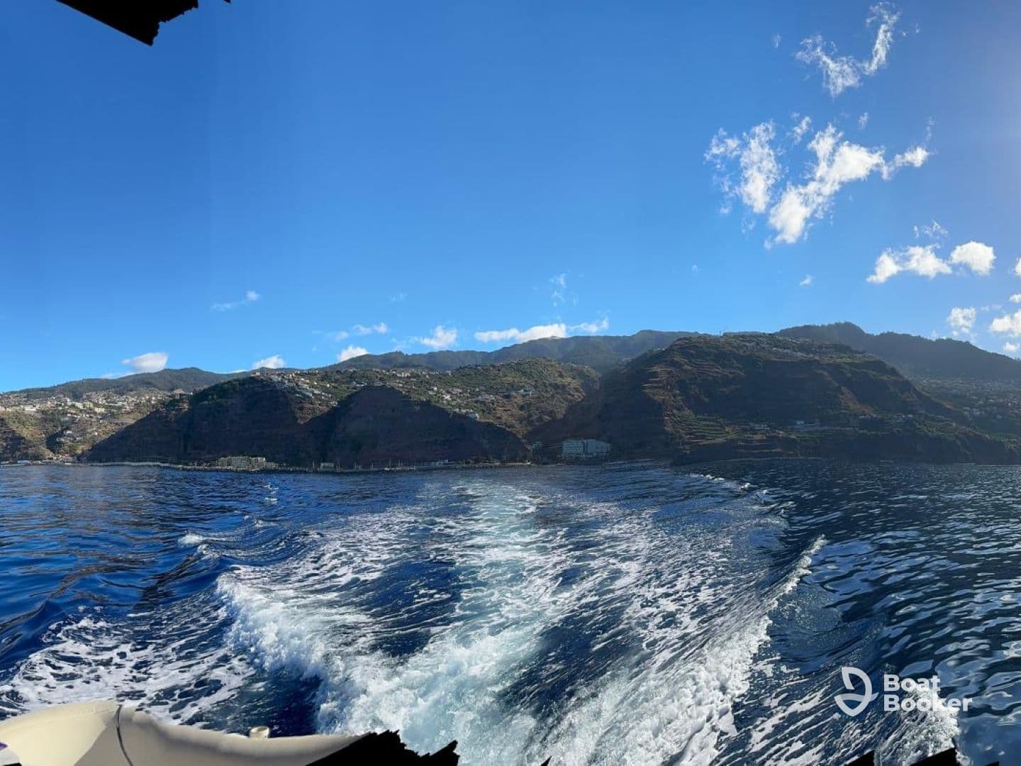 A stunning view of the coastline and mountains from a boat, showcasing the beautiful scenery of the ocean and landscape.