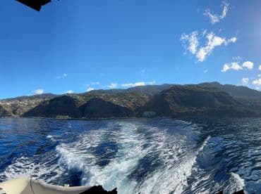 A stunning view of the coastline and mountains from a boat, showcasing the beautiful scenery of the ocean and landscape.