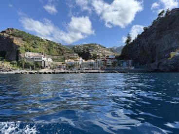 A stunning view of a coastal town nestled against the mountains, showcasing beautiful architecture and a serene harbor — perfect for exploring the scenic beauty of the region.