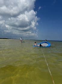A fun day on the water with friends, featuring paddleboarding and relaxing on a floating mat — perfect for summer adventures.