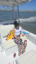 A mother enjoys a moment on a boat while holding her baby, showcasing a family adventure on the water.