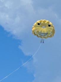 Two adventurers enjoy a thrilling parasailing experience high above the water, taking in breathtaking views while being towed by a boat.