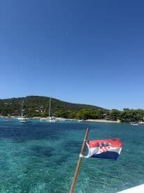 A picturesque view of a Croatian coastline with sailboats anchored in clear turquoise waters, perfect for sailing adventures and island exploration.