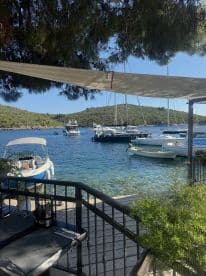 A serene view of various boats docked in a picturesque harbor, surrounded by lush greenery and clear waters, perfect for a relaxing day by the sea.