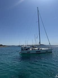 A beautiful sailboat glides through clear waters under a bright blue sky, showcasing the perfect setting for a sailing adventure.