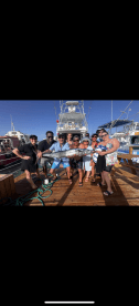 A lively group celebrates their fishing catch on the dock, showcasing camaraderie and excitement after a successful day on the water.
