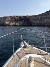 A clear view of the bow of a boat cruising near a rocky coastline, showcasing the vessel's design against a stunning natural backdrop.