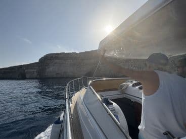 Two individuals navigate a boat near stunning cliffs, capturing the essence of adventure on the water.