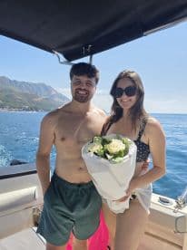 A couple celebrates a special moment on a boat, with one holding a bouquet of flowers — perfect for romantic getaways or memorable occasions on the water.
