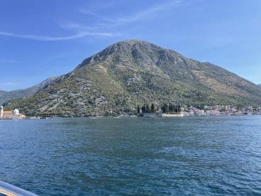 A stunning view of a mountainous coastline with a picturesque island and charming village, perfect for exploring the natural beauty of the region.