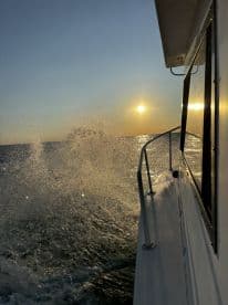 A stunning view of a boat cutting through the water at sunset, capturing the beauty of the open sea and the shimmering waves.
