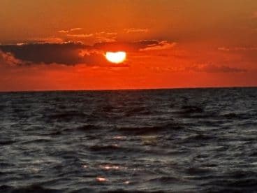 A breathtaking sunset over the ocean, casting vibrant hues across the sky and water — a perfect moment for relaxation and reflection on a boating adventure.