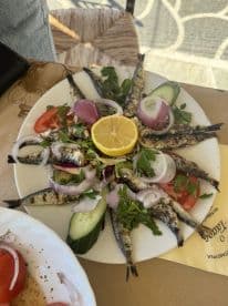 A beautifully arranged plate of grilled fish garnished with fresh vegetables and lemon, perfect for enjoying onboard or at a seaside restaurant.
