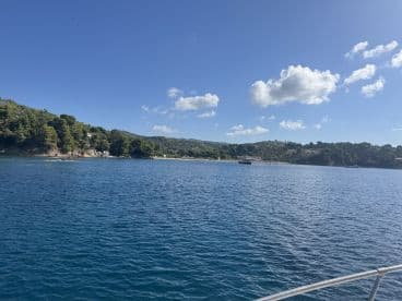 A picturesque view of a serene coastline with lush greenery and calm waters, perfect for a relaxing day on the boat.