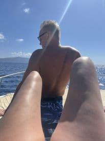 A couple enjoys a sunny day on a boat, capturing a moment of relaxation with the ocean in the background — perfect for a romantic getaway.