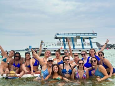 A lively group of friends celebrates together in the water, enjoying drinks and fun under the sun — perfect for bachelorette parties or summer getaways.