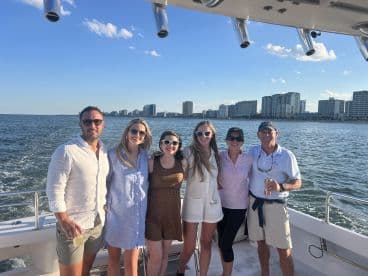 A cheerful group of friends enjoys a day on the water, posing for a photo with a stunning city skyline in the background — perfect for memorable outings and celebrations.
