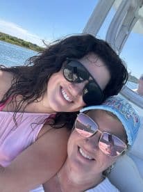 Two friends enjoy a sunny day on the boat, capturing a joyful moment with smiles and reflections in their sunglasses — perfect for memorable outings on the water.