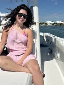 A woman enjoys a sunny day on a boat, smiling and relaxing in a stylish outfit — perfect for a day out on the water.