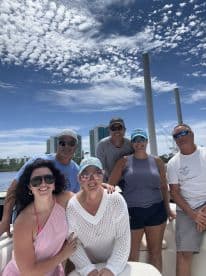 A cheerful group of friends poses for a photo on a boat, enjoying a sunny day out on the water — perfect for creating lasting memories together.