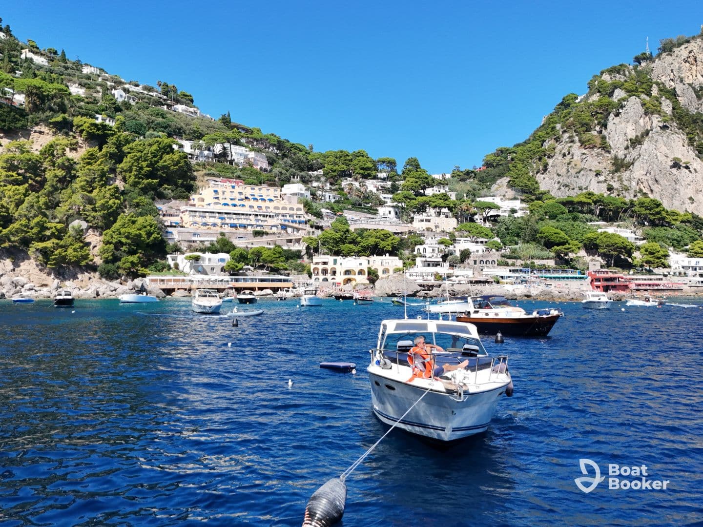 A scenic view of a coastal town with boats anchored in the clear blue waters, showcasing a relaxing day on the water.
