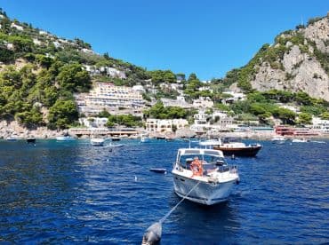 A scenic view of a coastal town with boats anchored in the clear blue waters, showcasing a relaxing day on the water.
