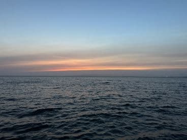 A serene view of the ocean at dusk, showcasing a beautiful gradient of colors in the sky. Ideal for capturing the tranquil essence of a sunset on the water.