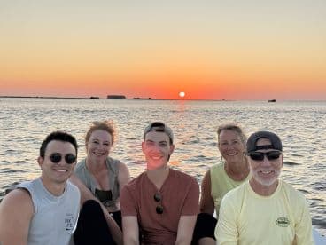 A cheerful group of friends enjoys a stunning sunset on the water, capturing the essence of memorable boat outings and shared experiences.