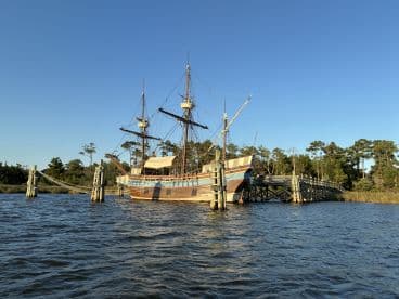 A stunning view of a historic ship docked at a pier, surrounded by serene waters and lush greenery, perfect for maritime enthusiasts and photographers.